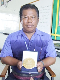 Pitak Sritang, assistant band instructor of Pattaya City School 4, and one of the Pattaya City School Band instructors, shows off the gold medal from the competition.